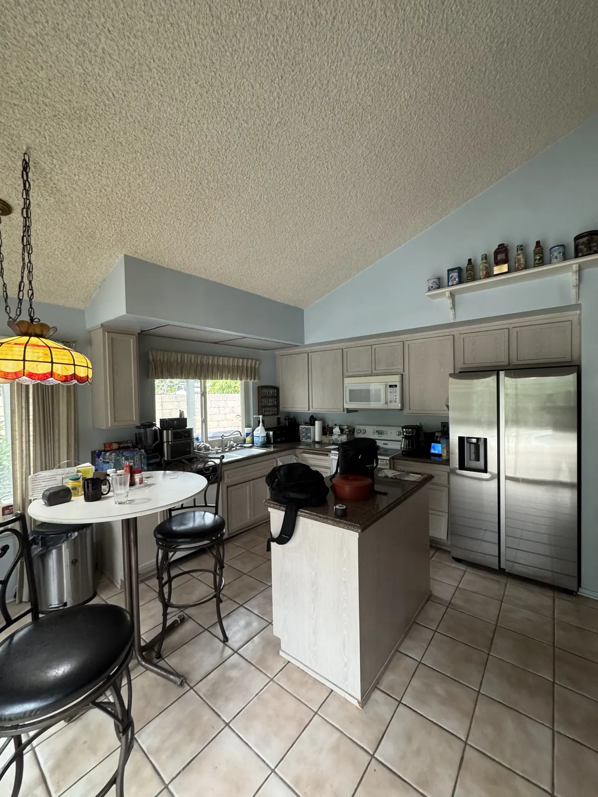 Before: kitchen with vaulted ceiling, original cabinets, an island and a tile floor