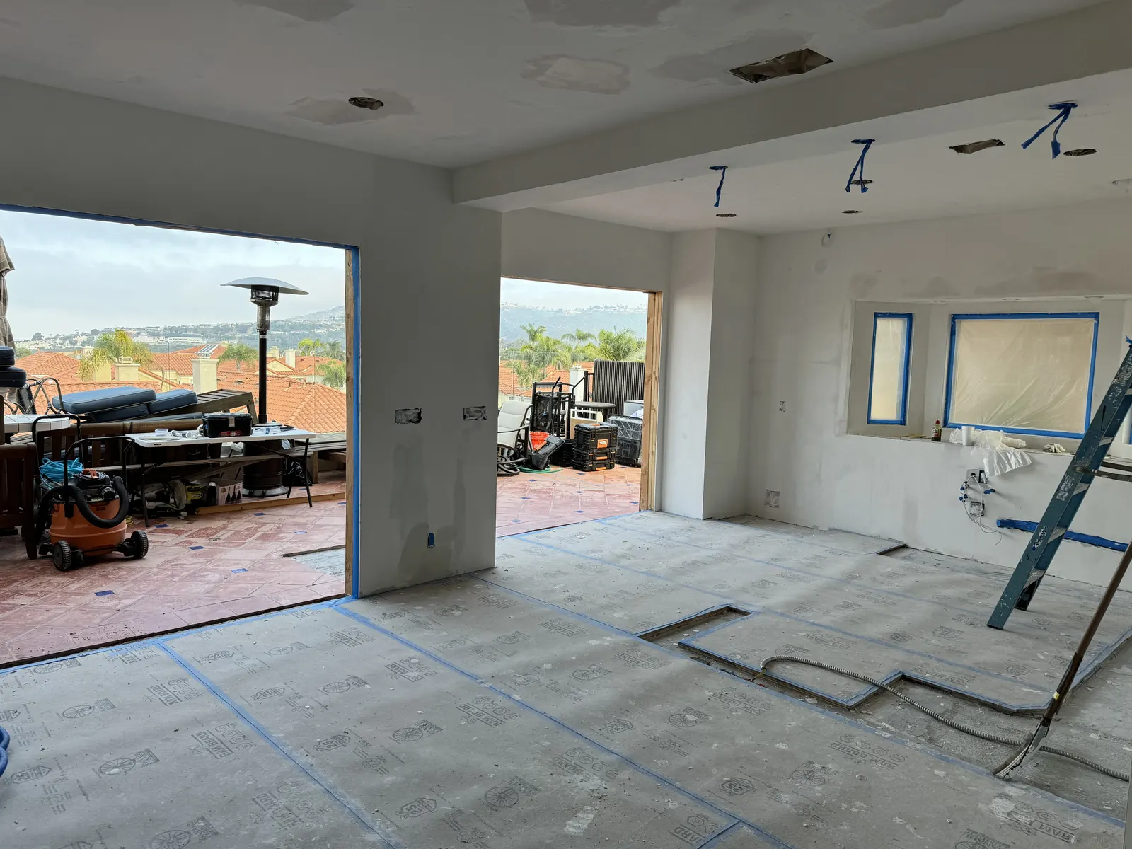 Before: room with large wall openings cut through to a patio and the floor covered in protective paper