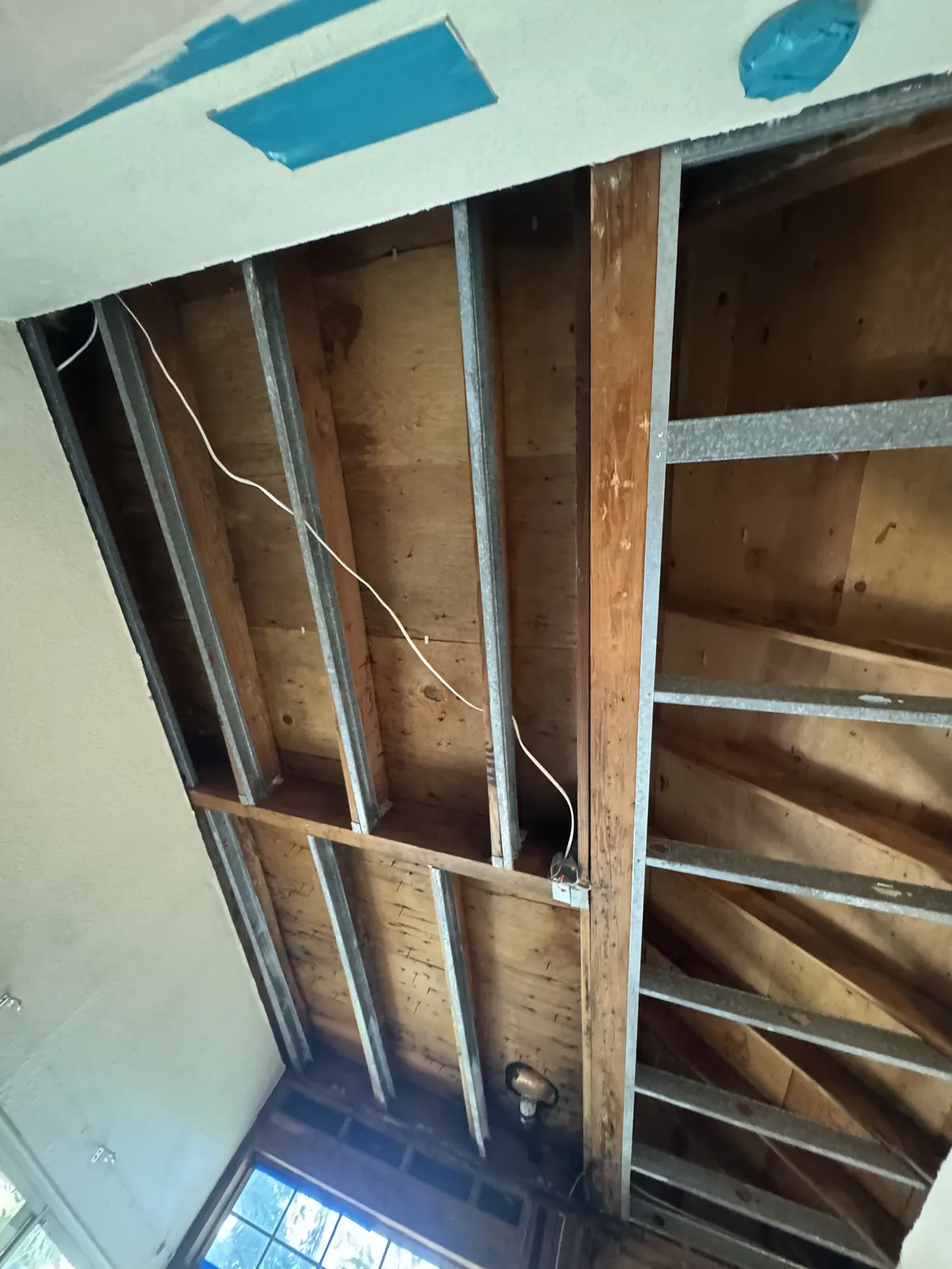 Ceiling drywall removed, exposing the wood joists and framing above