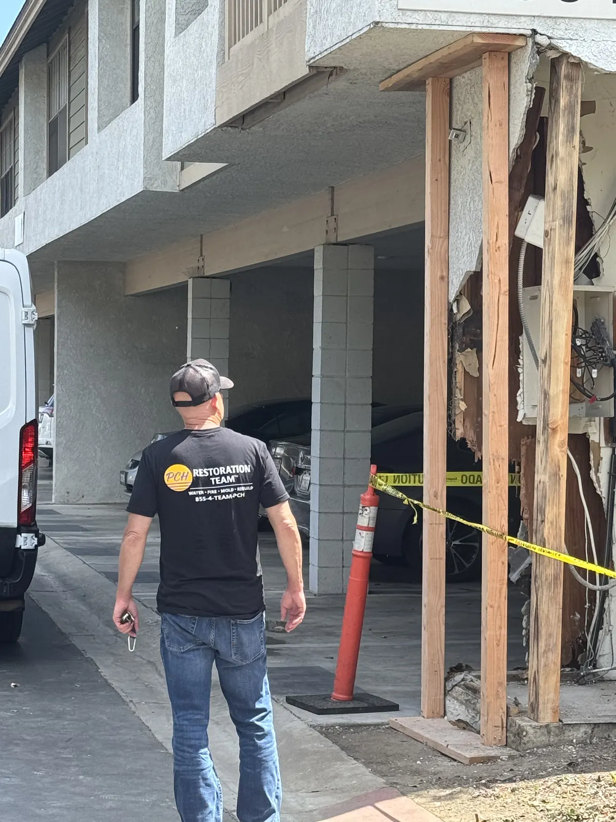 Temporary wood support posts installed at an opened carport wall, with a crew member nearby