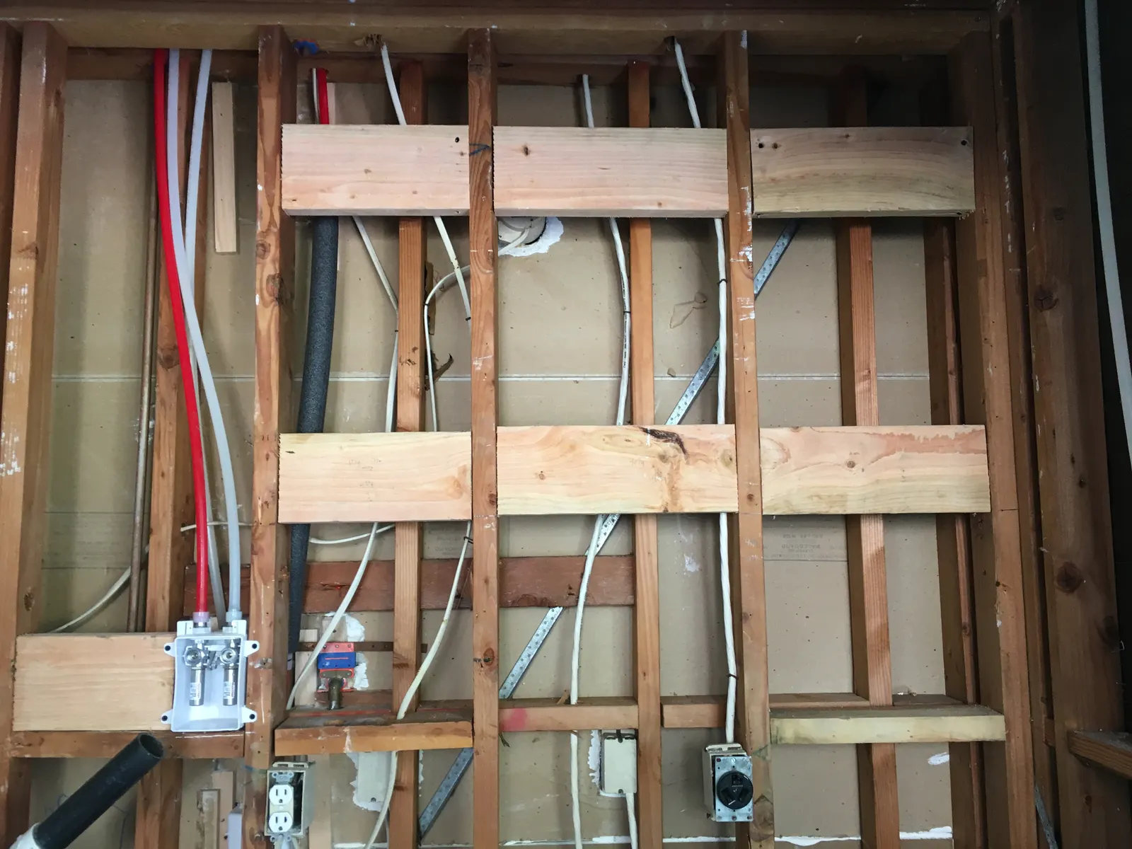 Opened wall showing studs, new wood blocking and electrical wiring