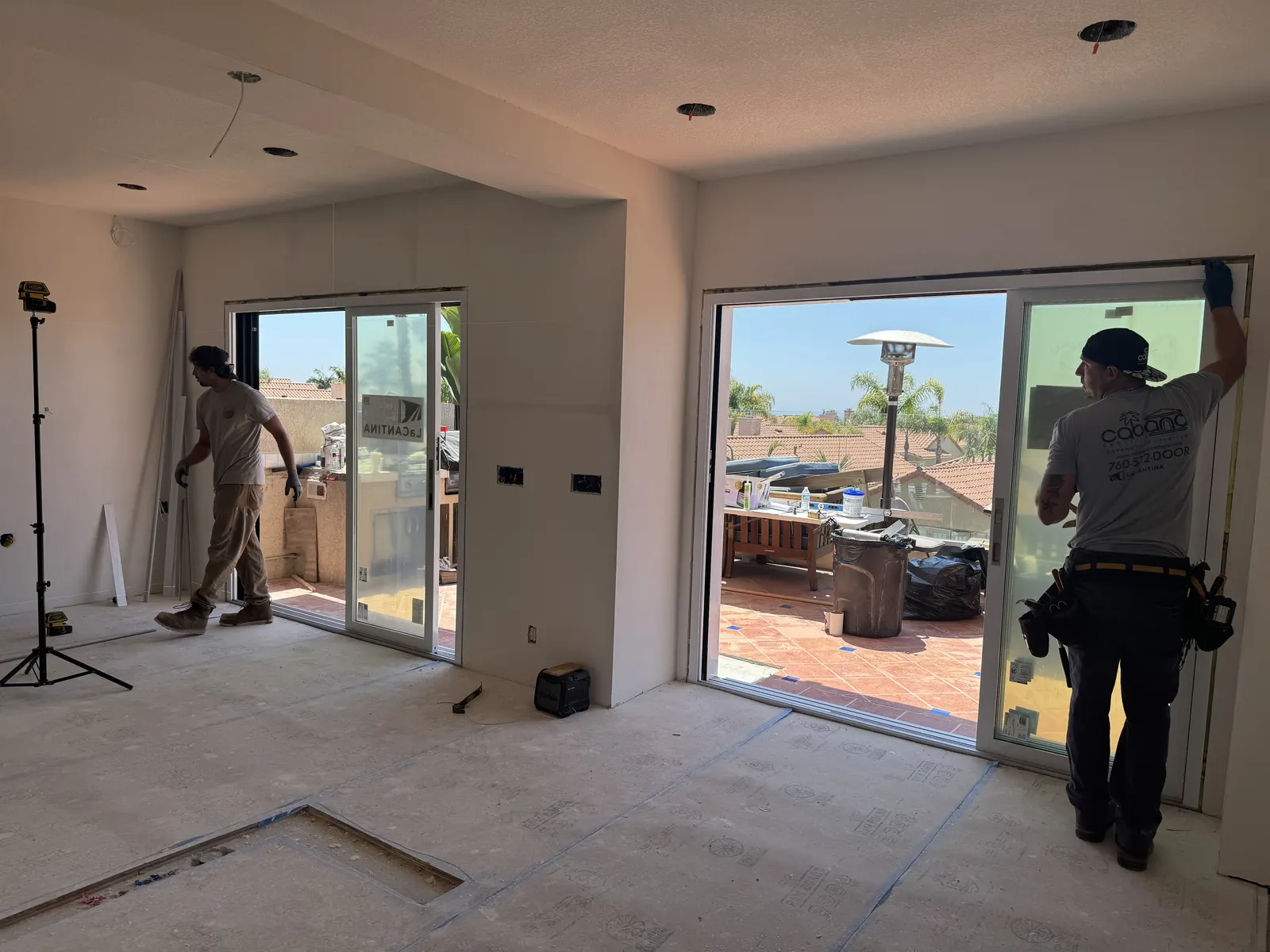 Crew members installing new sliding glass doors in a room with protected floors