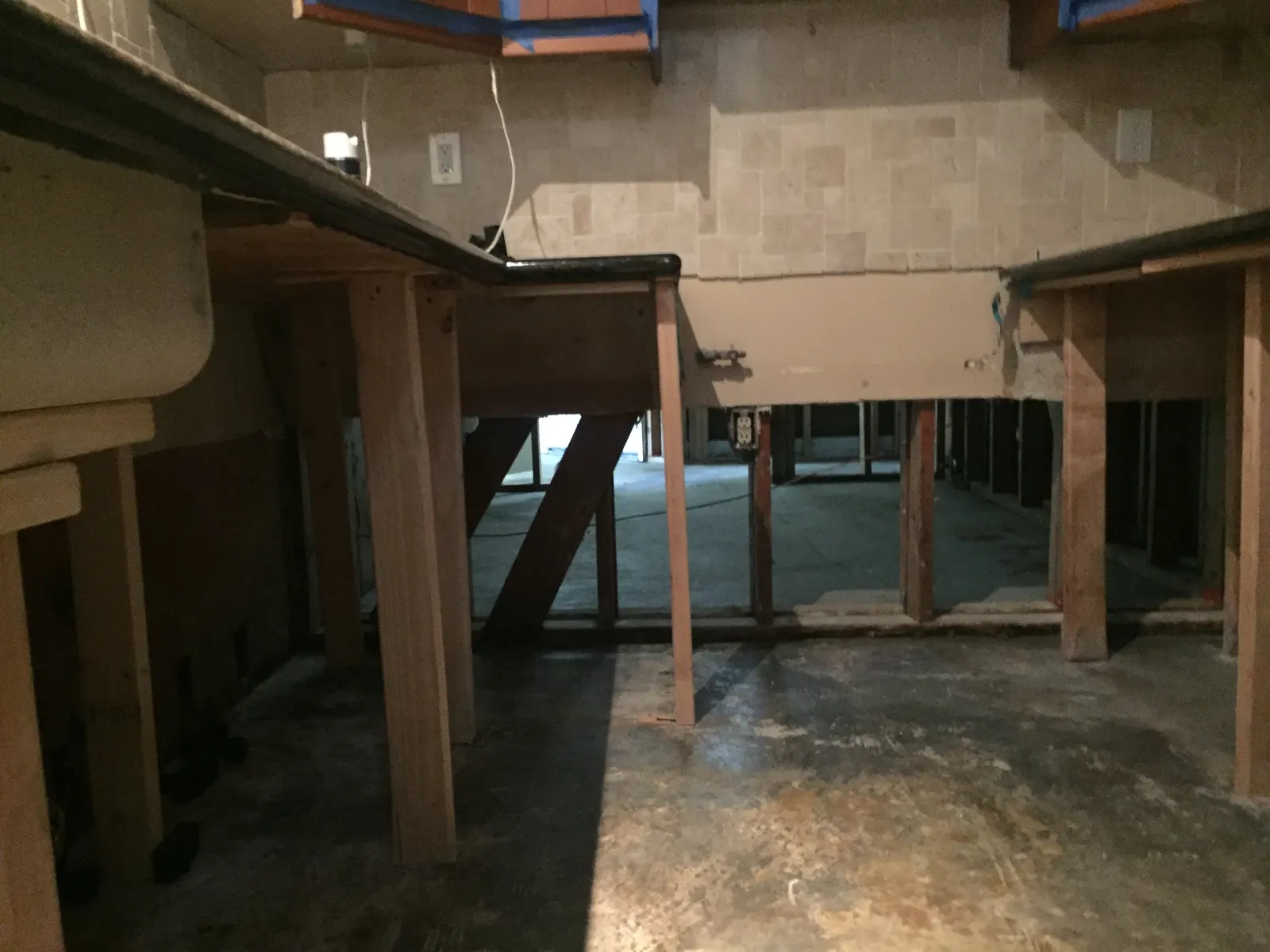 Kitchen with the lower cabinets removed and the countertops held up on temporary wood supports