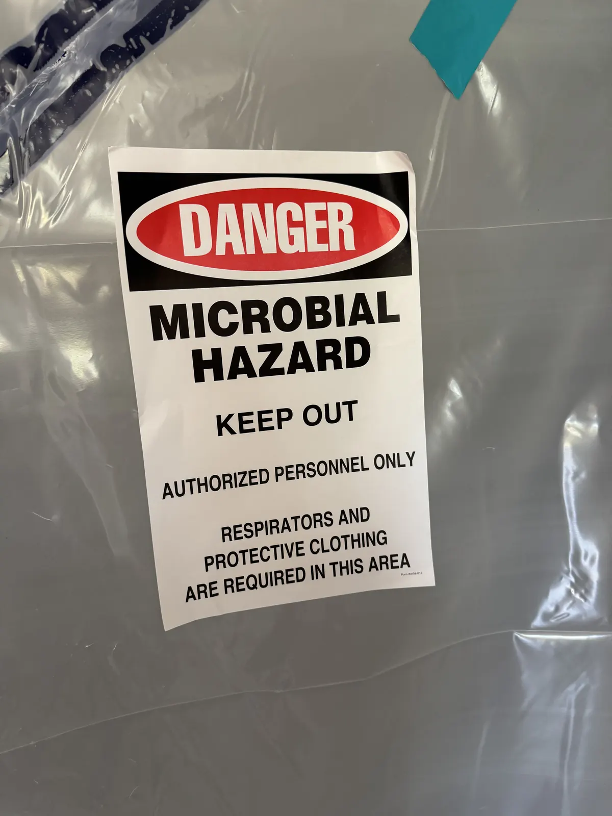 Microbial hazard keep-out sign posted on plastic containment sheeting