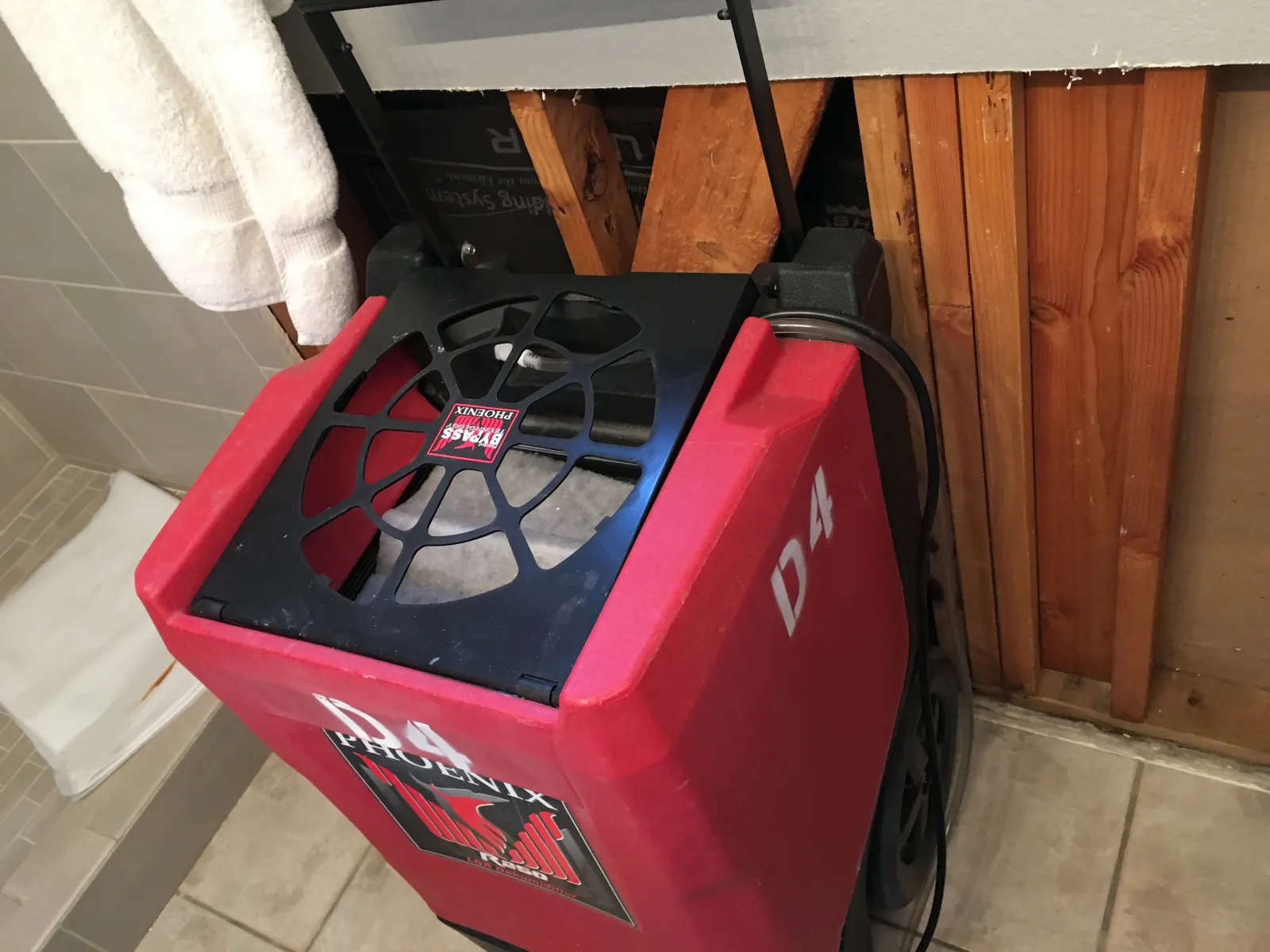 Red dehumidifier placed beside a wall with the lower panels removed