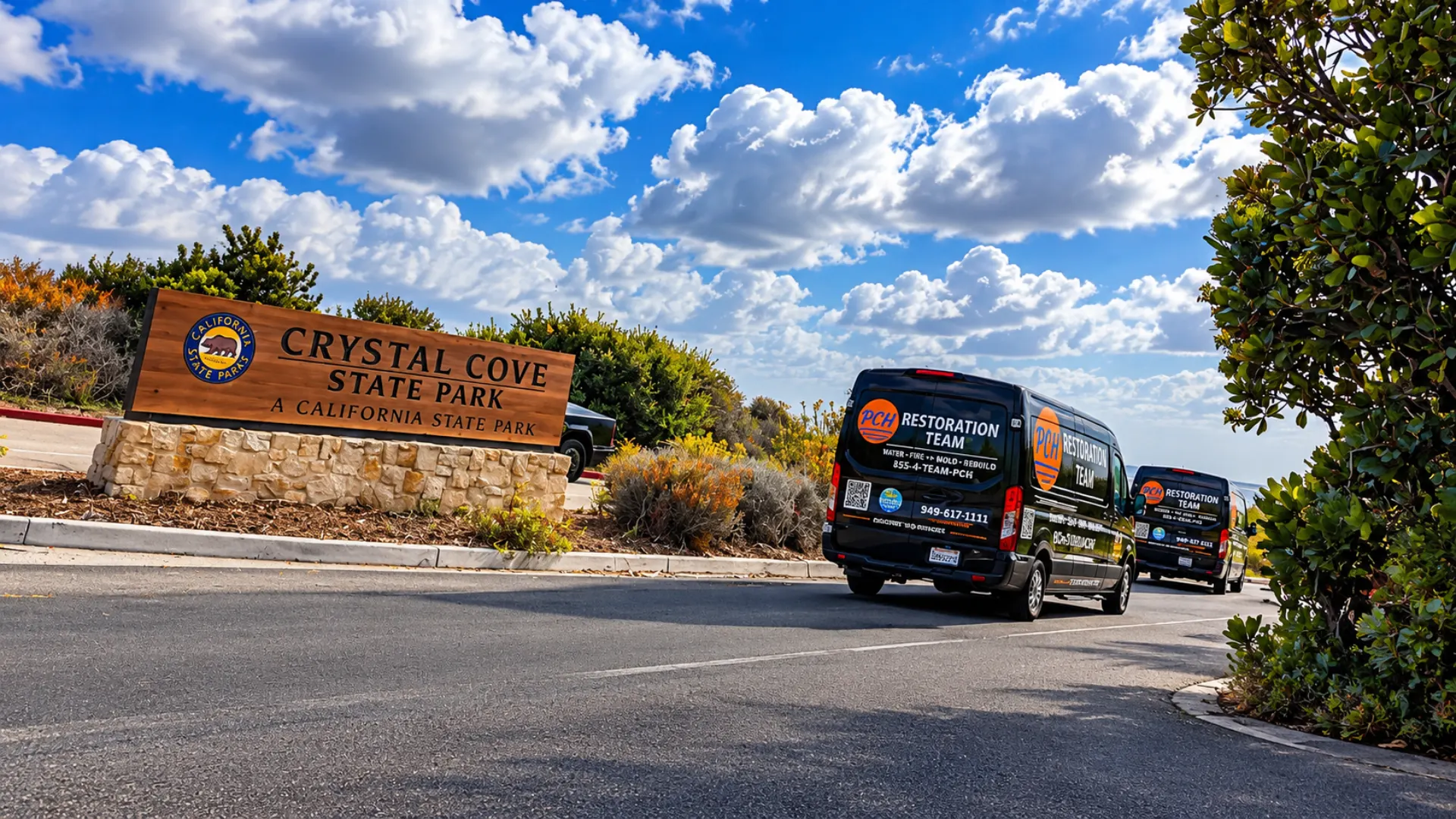 Two PCH Restoration Team vans parked along a coastal road under a cloudy sky