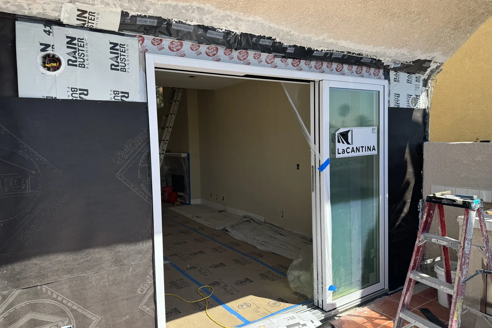 New folding glass door installed in a reframed opening wrapped in weather barrier during reconstruction