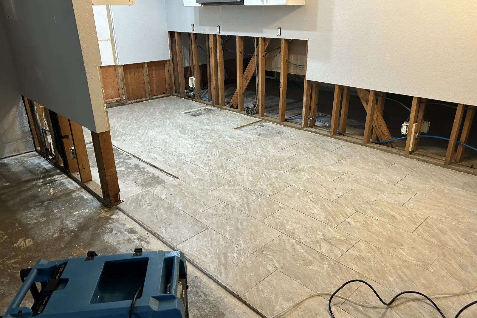 Flood-cut kitchen walls with exposed studs and drying equipment on the floor during water damage restoration